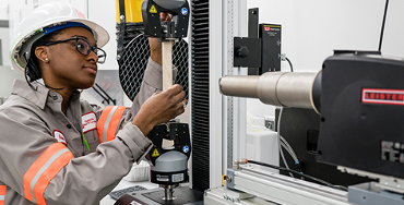Young black woman operating a machine in a factory setting