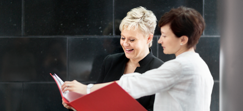 Two women talking and looking at document.