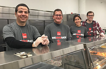 Four Toledo employees stand behind a lunch counter