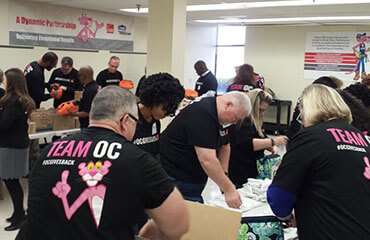 Fairburn employees look down at their tables and  assemble hygiene kits