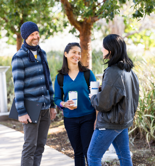 Three Amgen employees speak to each other outside at ATO campus.