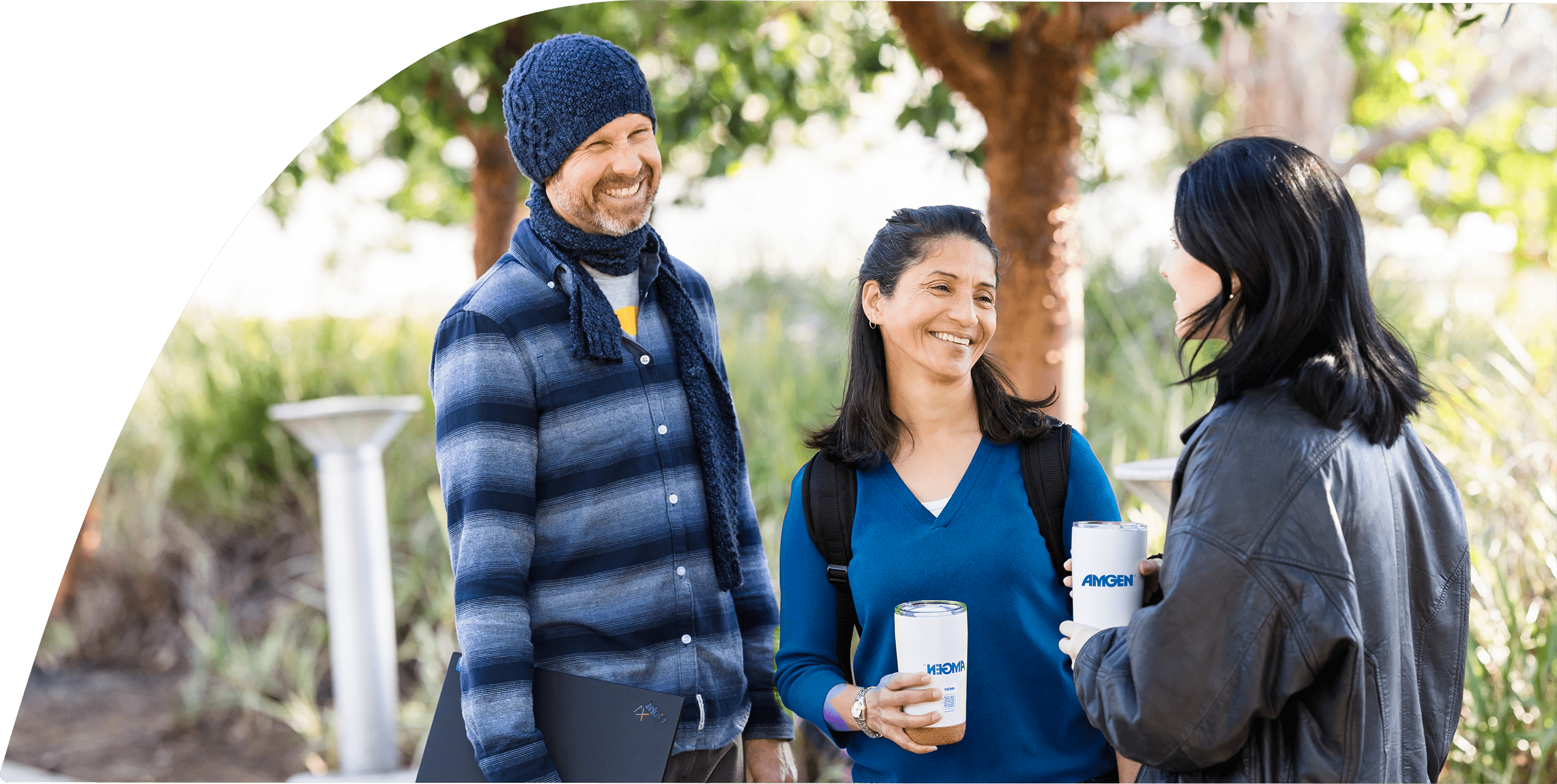 Three people in casual attire are standing together and smiling while talking