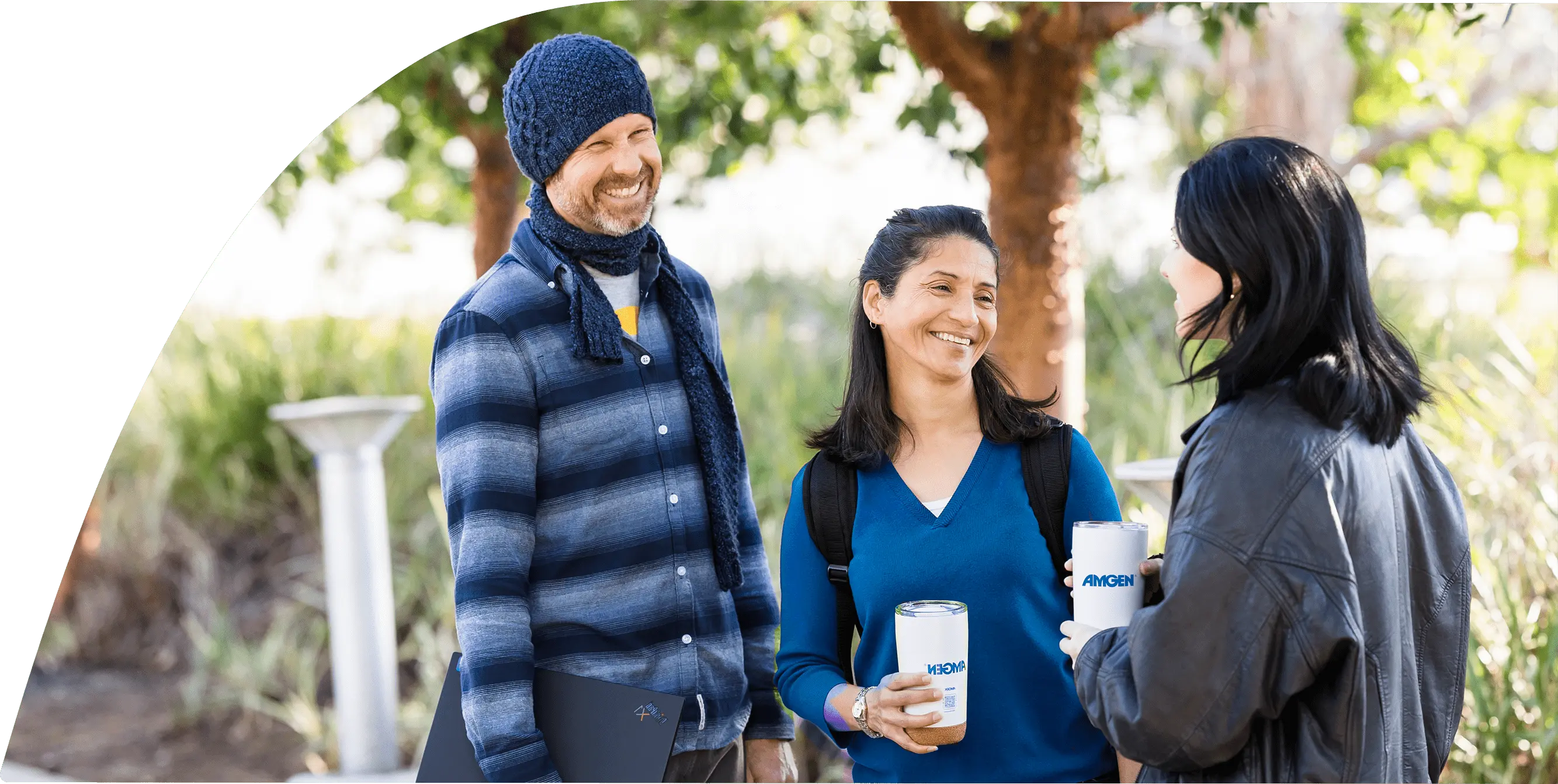Three people in casual attire are standing together and smiling while talking