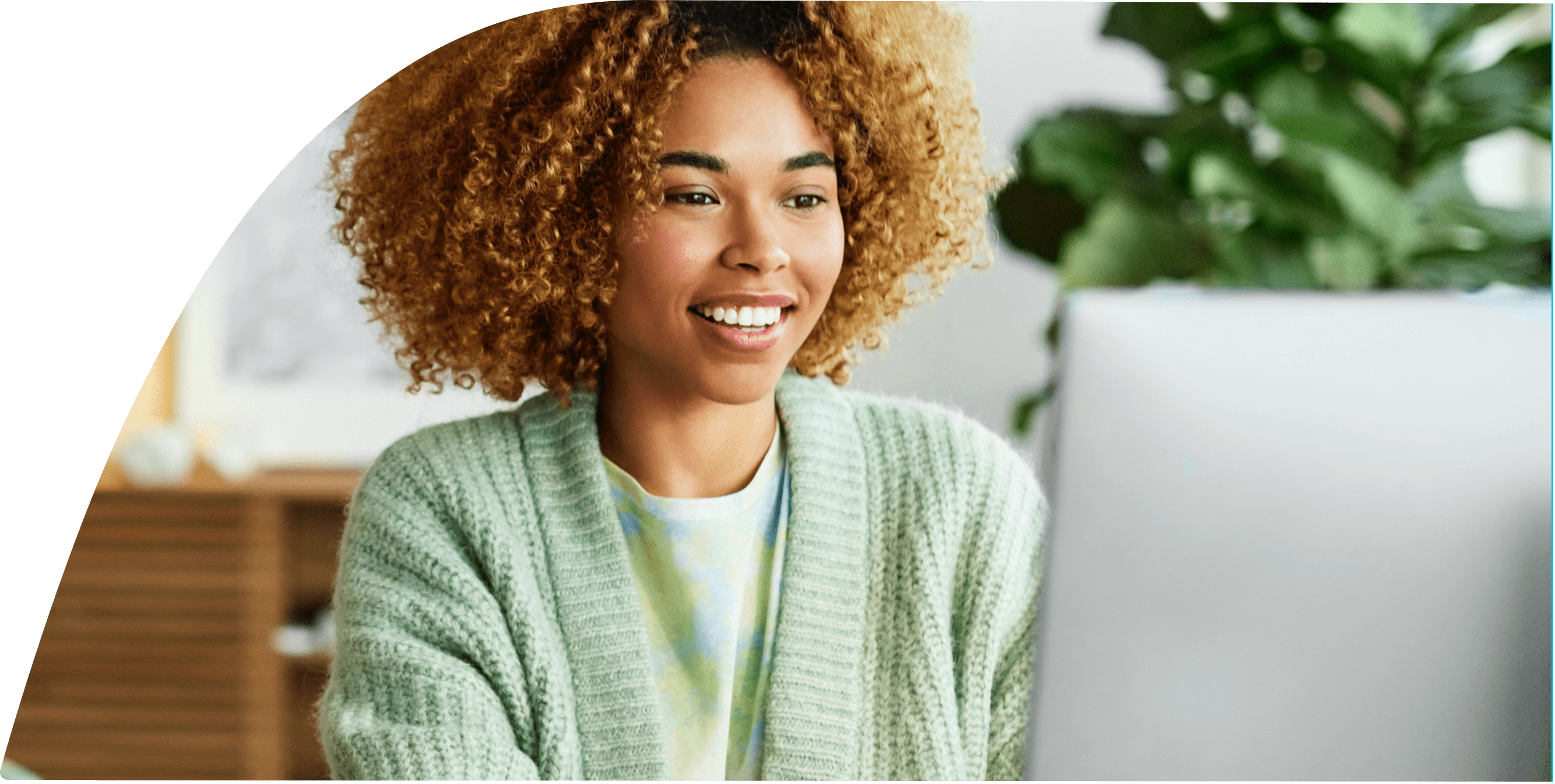 A woman is smiling while browsing on her computer