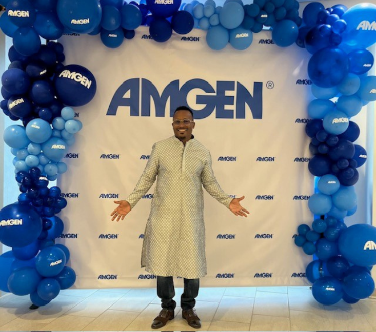 Aaron posing in front of an Amgen sign.