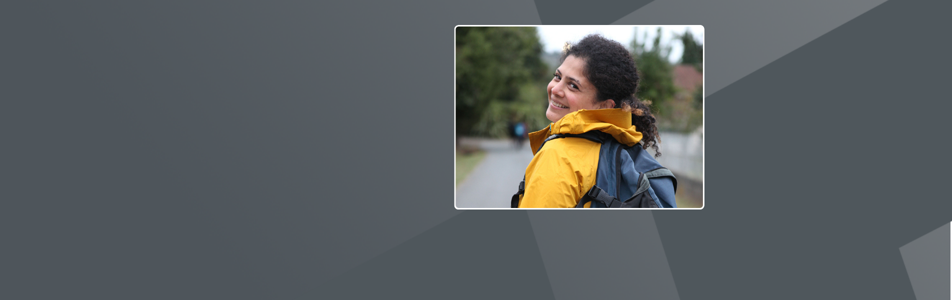 Chrishni outside, with a backpack and a bright yellow outdoor jacket.