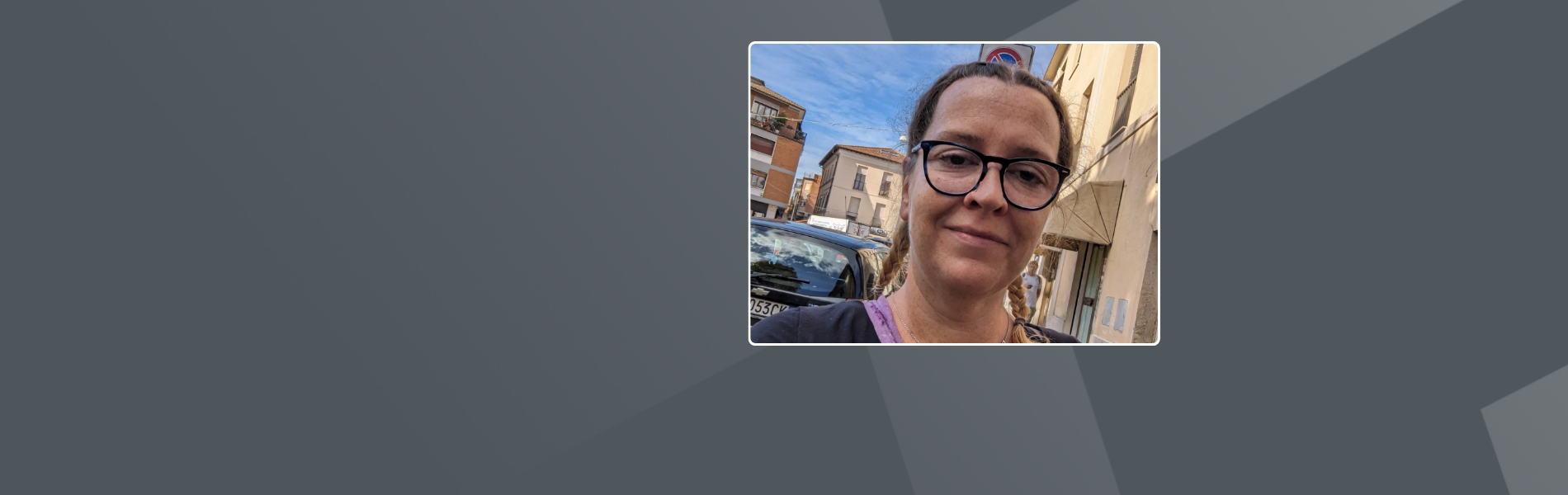 Julie, a female white German, wearing glasses and braided hair, standing in a street.