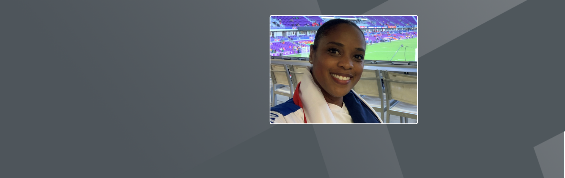 Yoela, a Black American female, smiling towards camera with her hair tied back.