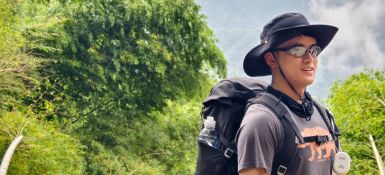 在山上一位男士戴着一顶帽子并背着登山背包