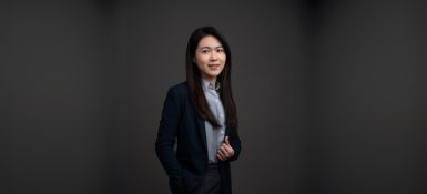 一位女士留着黑色长直发,穿着浅蓝色衬衫和黑色西装外套