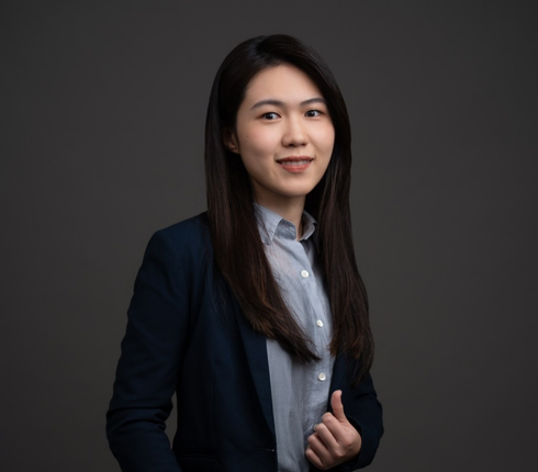 一位女士留着黑色长直发，穿着浅蓝色衬衫和黑色西装外套