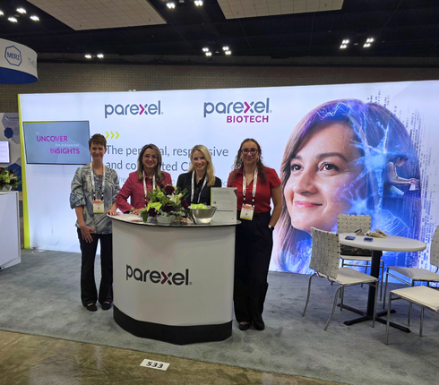 Parexel exhibition booth with four staff members, including Diana, at a rounded counter. Display features Parexel and Parexel Biotech branding with "Uncover Insights" tagline and digital graphic of Diana.