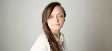 Diana, a Columbian woman with long brown hair is wearing a white blouse.