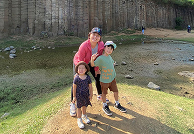 Joy Lin, Senior Director of Statistical Programming, is outside with her two young children in nature.