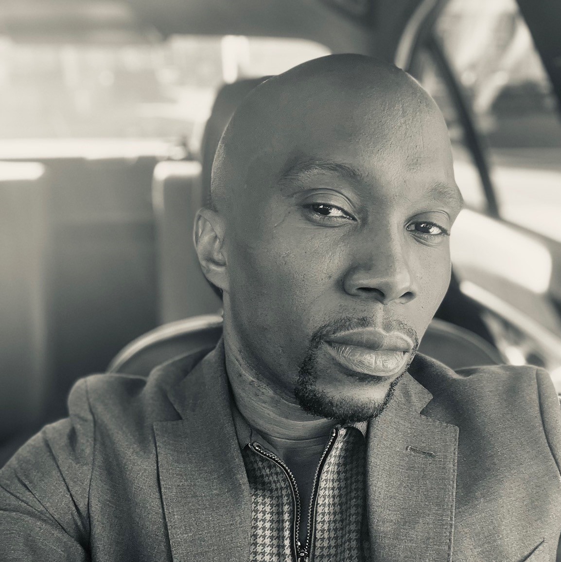 Laurias Eugene, a clinical operations manager in Parexel is looking at the camera. He is wearing casual wear and is in a car.