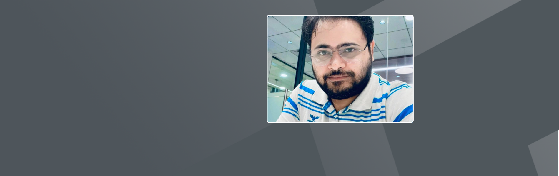 Shadaab, an indian male, with short dark hair, glasses and a beard, wearing a blue and white shirt