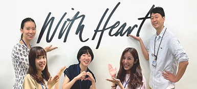 A group of Parexel colleagues in front of a With Heart™ sign