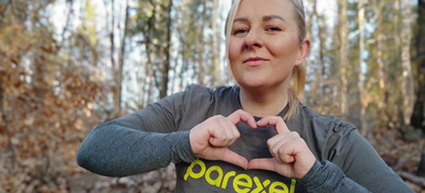 Laura at the Rare Disease Run 2024, wearing a Parexel t-shirt and shaping a heart with her hands.