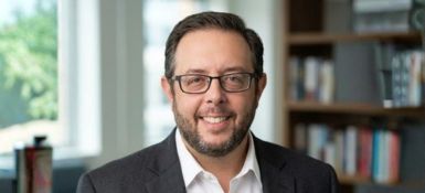 Michael Bossio, brown hair with glasses, wearing a black jacket and white button-up shirt