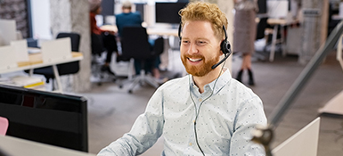 Male employee sitting at desk with headset on