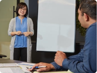 Two employees in a conference room talking to each other.