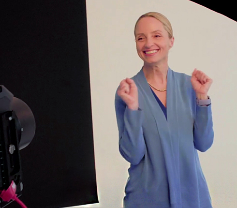 Anne, a white American woman wearing a blue blouse, during the photoshoot for the campaign. She is excitingly holding up her forearms.