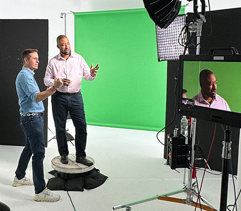 Moe, a black American colleague during the photoshoot for the campaign. You see Moe in the photo shooting scene with someone next to him giving instructions and cameras framing the picture.