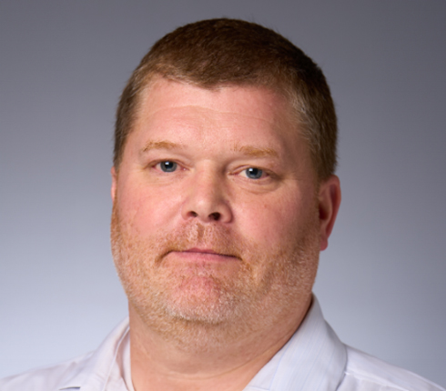 Todd, a white American man, with red hair and a beard, wears a white shirt.