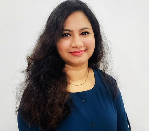 Picture of Bindu D smiling and looking at the camera. Long black hair and wearing a navy top.