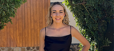 Danielle Jansen van Rensburg, Statistical Programmer, smiling at the camera with blonde curly hair and a black tank top