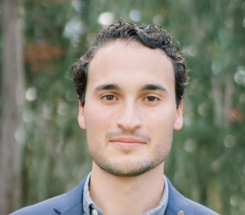 Doug Skinner, brown hair wearing a navy suit jacket and a light blue button up shirt