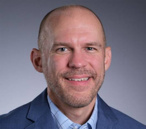 Jeff, a white American and Senior Director, Global Diversity, Equity and Inclusion, looking at the camera with a smile, wearing a shirt and jacket.