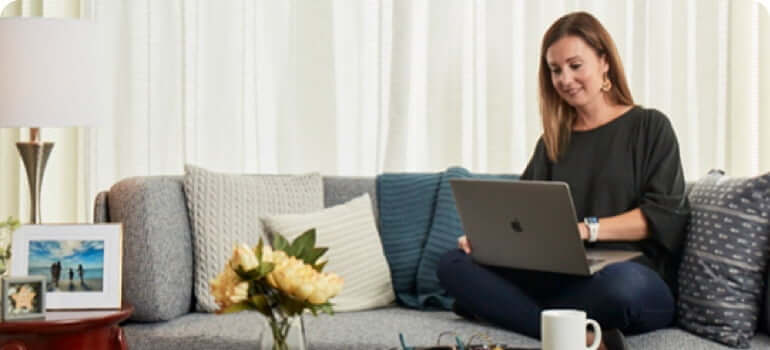 Woman seating on a couch working on a laptop