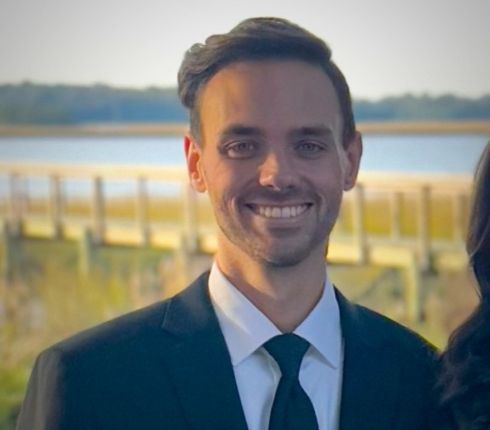 Kyle, brown hair and eyes, wearing a black suit