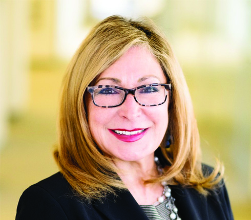 Aida Sabo, a Mexican American female working as Senior VP of Diversity, Equity & Inclusion (USA), with short blonde hair, brown glasses and business attire. She smiles while looking directly into the camera