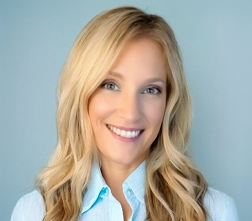 Jessica smiling towards camera. She has long blonde hair and is wearing a light blue collared shirt