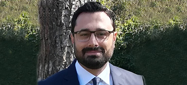 Sinan, VP-Technical of Regulatory Strategy, with short dark hair and beard, wearing black glasses and a professional attire. Smiling into the camera.