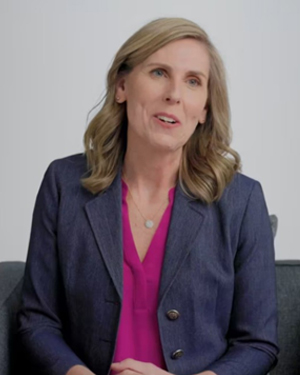 Stacy, a white female woman, long wavy blond hair, wearing a blue jacket and a pink shirt.