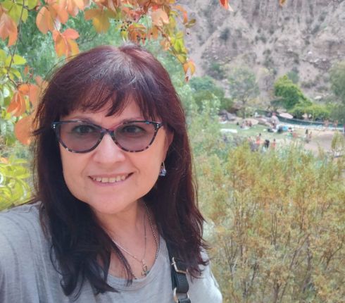 Zulma, long brown hair wearing glasses and a grey shirt