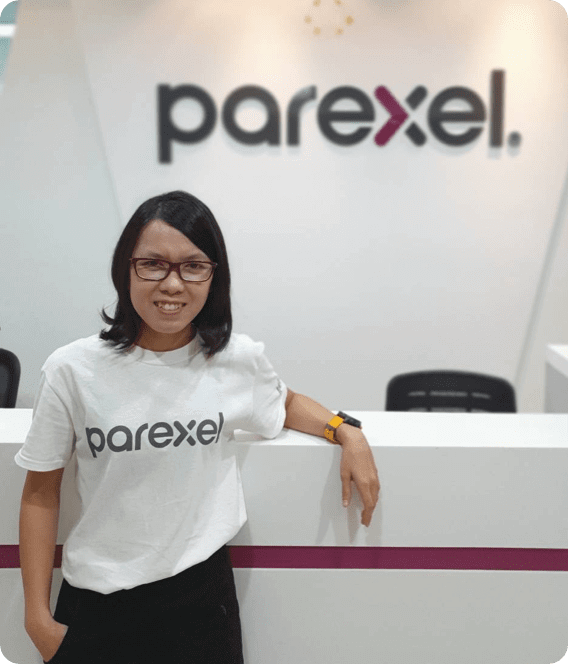 Female employee leaning on desk with Parexel logo in background