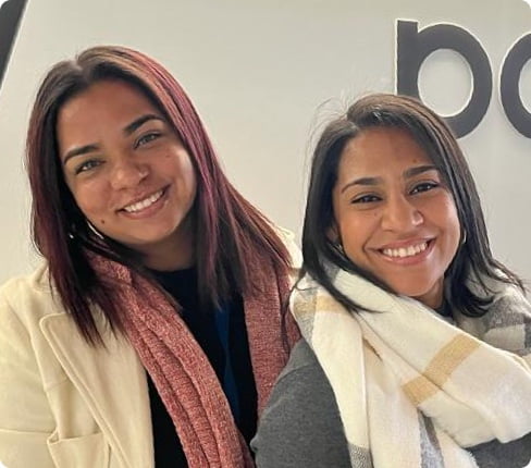 Cheri & Tarryn, two females from South Africa, one has dark brown and the other dark read hair, wearing scarfs and pullovers.