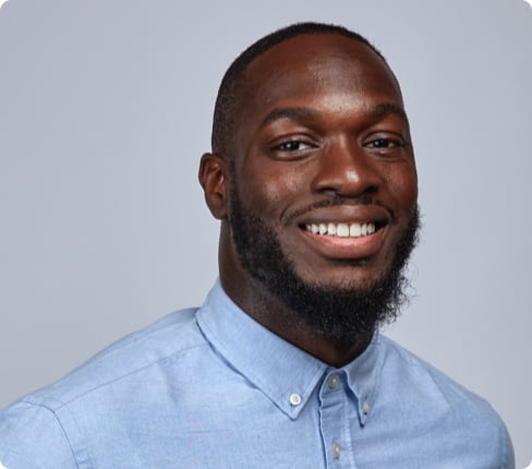 Henry, a male Black American, with short hair and a beard, wears a light blue shirt.