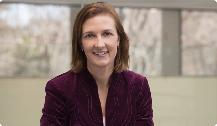 Amy Mykee, female American, wearing chin long dark blond hair, and a burgundy jacket.