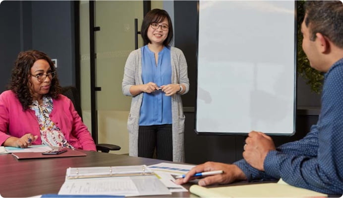 Sammy, a female Taiwanese and Project Leader at Parexel, is giving a presentation to people sitting at a table.