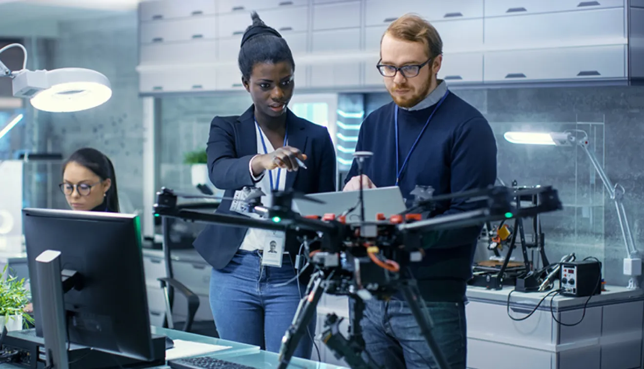 Guy holding computer standing with others