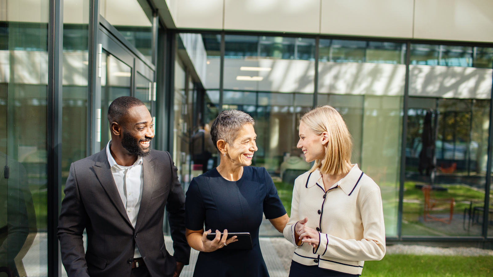 three young employees looking at a tablet and smiling
