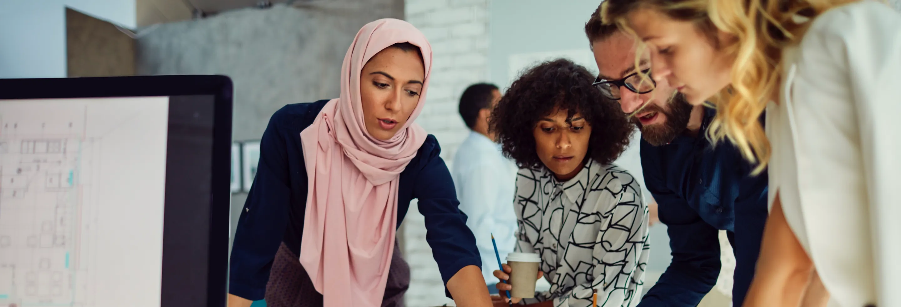 three employees meeting at a conference table in a sunlit office
