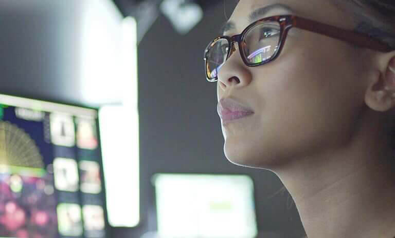 female employee looking at multiple computer monitors