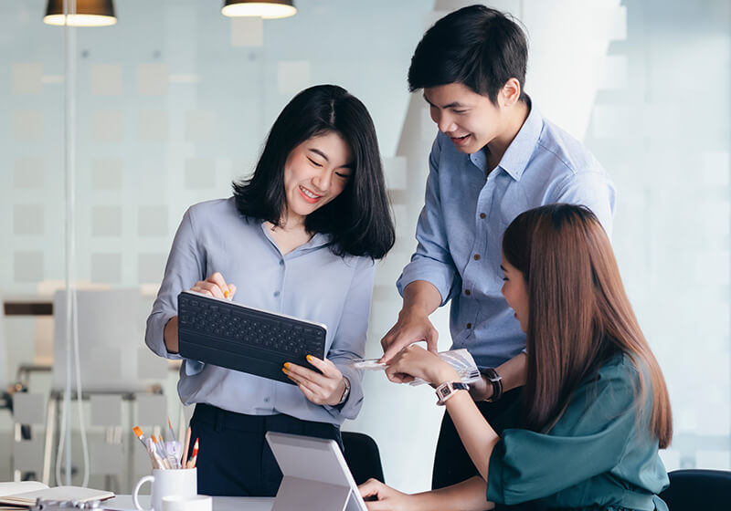 three young employees looking at a tablet and smiling