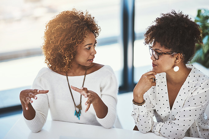 two young black female employees discussing an idea together